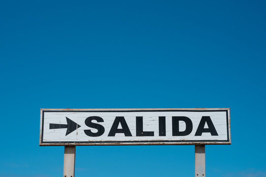 Exit sign (spanish: SALIDA) isolated on blue sky  