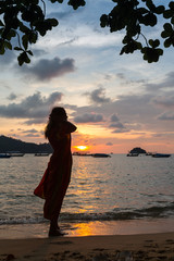 Fototapeta premium Young female model in the white dress and brown sunglasses enjoys the last rays of the sun.