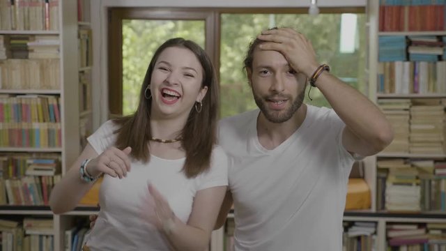 Embarrassed millennial man slapping his forehead doing facepalm next his girlfriend happy funny couple having fun
