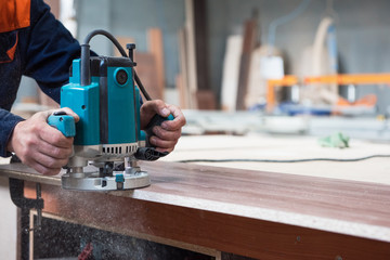 Furniture production or craft concept: worker polishing the wood surface of furniture part with polish machine