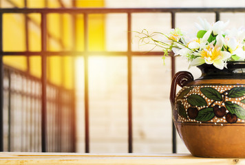 beautiful white flowers on clay vase with cherry fruit painting above wood table