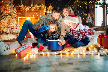 Family playing with gifts on the floor indoors on Christmas Day.