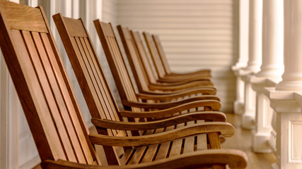 wooden rocking chairs in a row on a veranda with blurred background