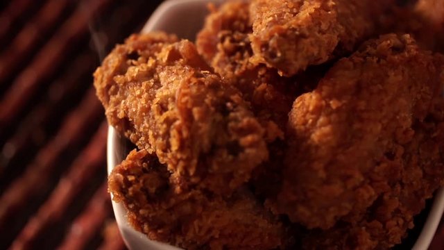 Rotation Bucket full of crispy kentucky fried chicken with smoke on brown background.