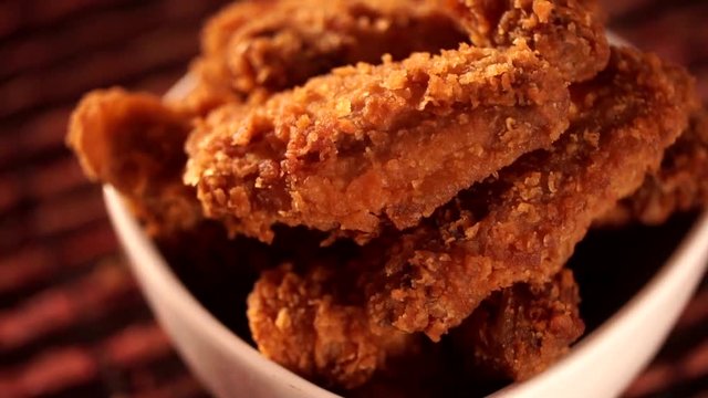 Rotation Bucket full of crispy kentucky fried chicken with smoke on brown background.
