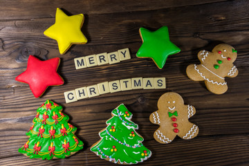 Tasty festive Christmas gingerbread cookies and Merry Christmas inscription on wooden table. Top view