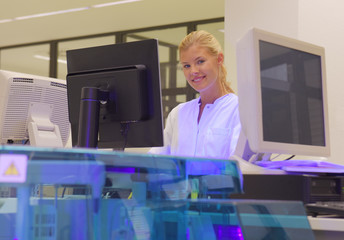 A young woman takes up her duties as  lab technitian. She wears a white smock to work with while...