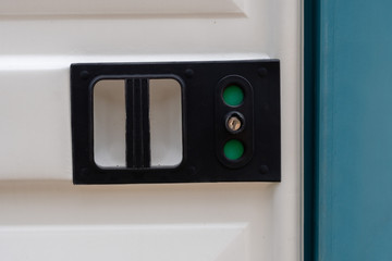 Close-up of a portable toilet door lock with green sign