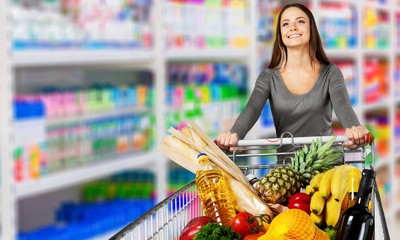 Young happy woman pushing shopping cart