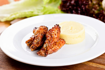 Chicken drumsticks and mashed potatoes on white plate. Close up