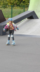 Little girl riding on roller skates in a helmet and knee pads