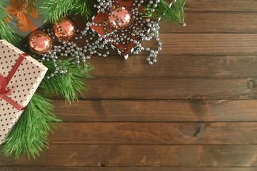 Christmas still life with gift box and Christmas balls and beads on a wooden table against the background of pine branches. View from above. Copy space.