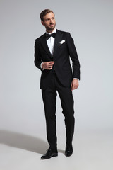 elegant man in tuxedo walks to side and looks away
