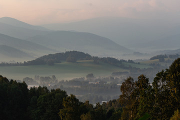 Dramatic mountain landscape before the storm - heavy gray clouds float above the green wooded hills to the horizon.