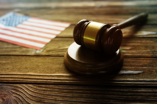 Judge's gavel, flag of the United States of America against the background of a wooden table. jurisprudence, legislation.
