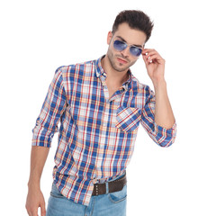 portrait of man wearing shirt with checkers fixing his sunglasses