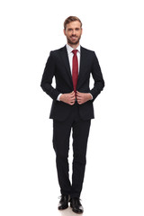 young smiling businessman buttoning his suit while standing
