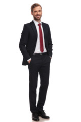 relaxed businessman smiling and standing with hands in pockets