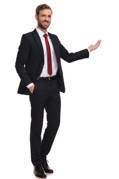 Businessman Stands With Hand In Pocket And Presents To Side