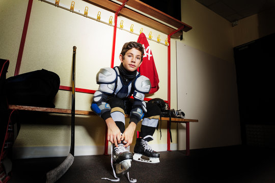 Boy ties hockey skates laces in dressing room