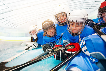 Joyful kids in hockey uniform laying on ice rink