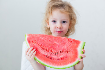 cute little baby girl eating watermelon slice on light background