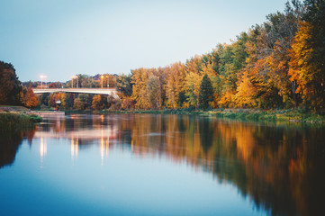 Neris river with golden autumn trees and bridge reflected in the water during twilight blue hour in Vilnius Lithuania