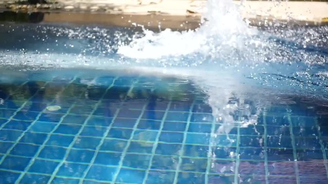 A man in red shert dives upside down in a blue pool. HD, 1920x1080, slow motion