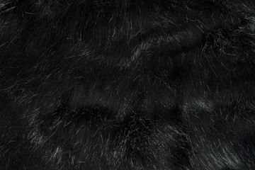 Highly detailed background texture of black fur made of synthetic animal long hair.