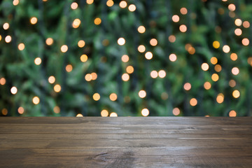 Blurred gold garland on Christmas tree as background and wooden tabletop as foreground. Christmas abstract. Image for display or montage your christmas products. Copy space.