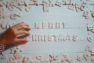 Merry Christmas 2019. Hand of woman writing Merry Christmas with white letters on white background. Christmas holiday.