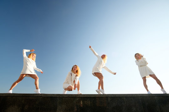 Multiplied collage of young redgead dancing girl, weared in white dress and sneakers, white blue sky background