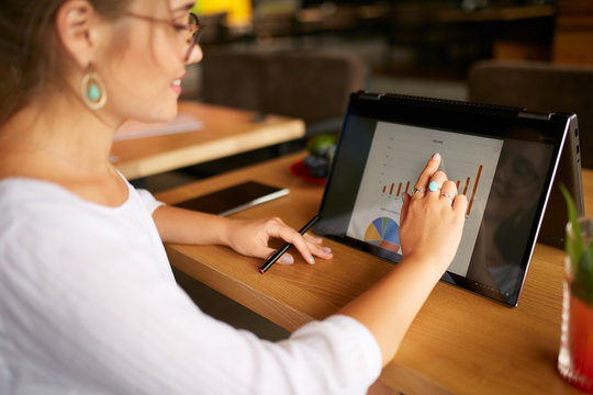 Businesswoman finger touching the chart over convertible laptop screen in tent mode. Freelancer woman using 2 in 1 notebook with touchscreen for work on business presentation. Isolated close view.