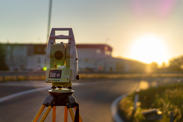 Surveyor equipment (theodolit or total positioning station) on the construction site of the motorway or road during sunrise