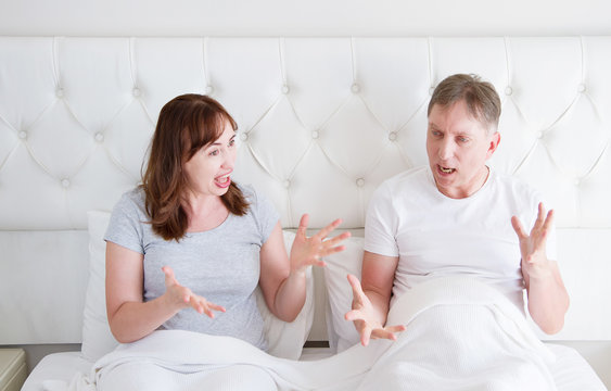 Caucasian middle age family couple angry shouting in bed. Conflict relationship concept. Husband and wife dialogue. Selective focus