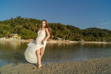 Fototapeta na wymiar Woman in white dress at the sea on the sunset on Palawan island, Philippines