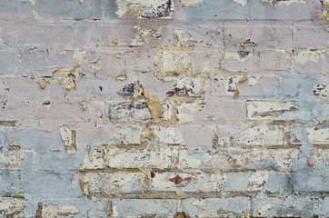 Pastel paint chips away from brick wall