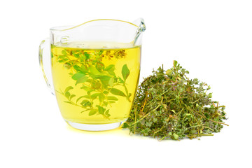 A Glass of Wild Thyme (Thymus) Tea Extract with a Heap Pile of Dried Herb. Isolated on White Background.
