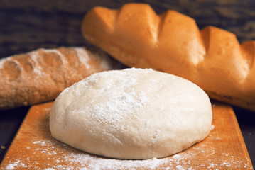 Dough on a wooden cutting board on the background of fresh bread