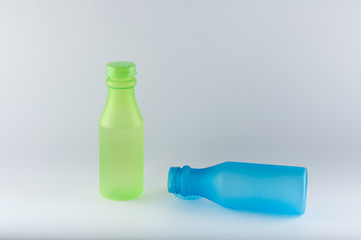 Green and blue plastic bottles on white background