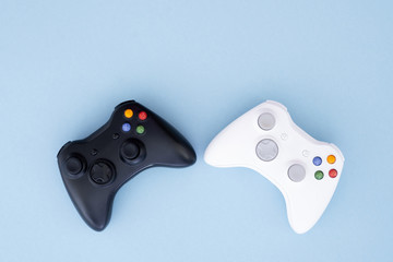 Two joysticks, black and white on a pastel blue background. White and black gamepad are isolated on a pastel blue background. Computer game competition. Gamer concept. Copyspace © bodnarphoto