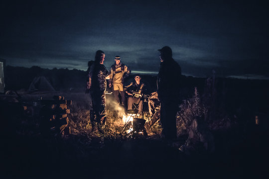 Group of men people travelers tourist resting camp fire in outdoors camp after long hunting day in the night   