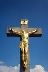 Golden Jesus Christ crucifixion statue, sunny summer day blue sky background, Vrbice, Moravia, Czech Republic