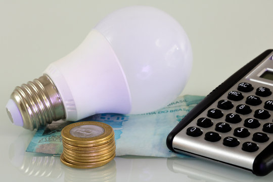 Real hundred notes, real coins and a lamp. Brazilian money. Energy Brazil.
