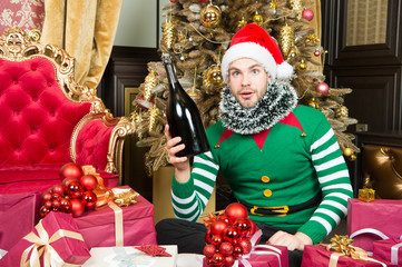 Obraz na płótnie Canvas Man enjoy christmas party celebration. Man in Santa hat hold champagne at christmas tree. Taking part in celebration. Party night. Lets stay near to celebrate the New Year