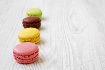 Sweet and colorful macarons on a white wooden table, side view. Copy space. Selective focus.
