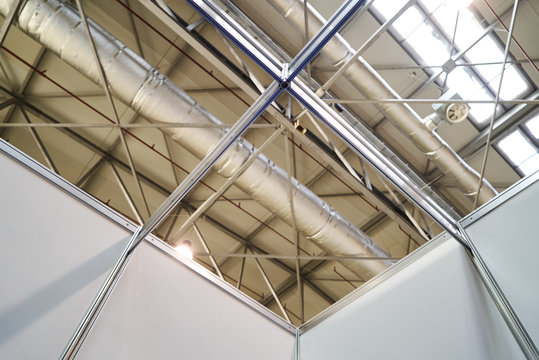 Ceiling Ventilation System. Bare skin ceiling, show roof structure and air condition system. International Exhibition furniture elements in large warehouse interior.