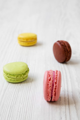 Sweet and colorful macaroons on a white wooden background, side view. Selective focus.