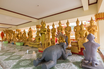 Two animal sculptures and many gilded Buddha statues at the Wat That Luang Tai Temple in Vientiane, Laos.