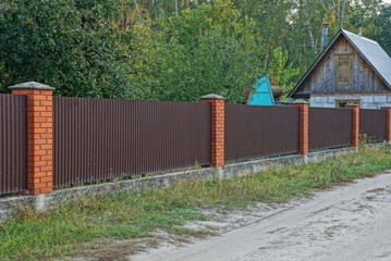 long brown metal and brick fence in the street by the road